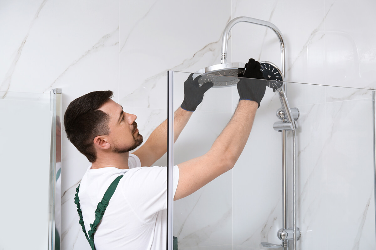 Professional handyman working in shower booth indoors